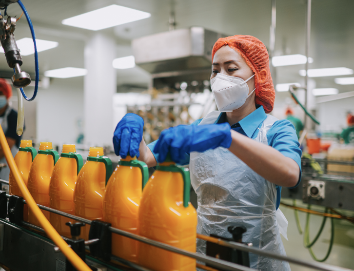 Asian Chinese female juice factory worker tighten bottle cap in production line
