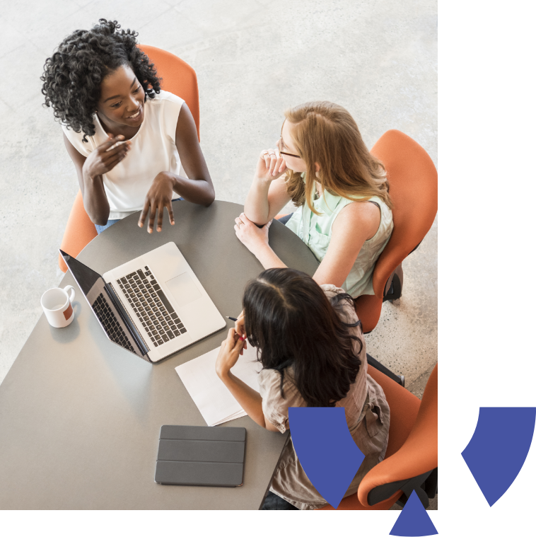 Multi racial women in business meeting on orange chairs with computer and tablet on table