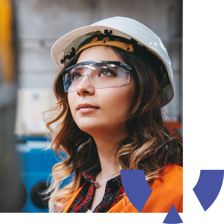 Portrait of young businesswoman with white helmet looking up and seen from the industrial steel cable reel for crane in factory warehouse
